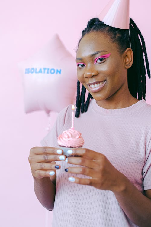 A Woman Holding a Cupcake while Smiling at Camera