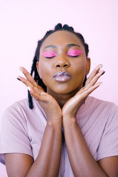 Close-up of an African American woman with vibrant pink eye makeup and serene expression.