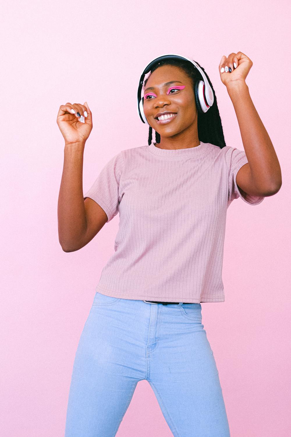 woman dancing with headphones on and a light pink backdrop
