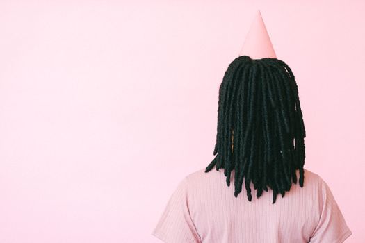 粉红色背景下，一个留着辫子、戴着派对帽的女人背影