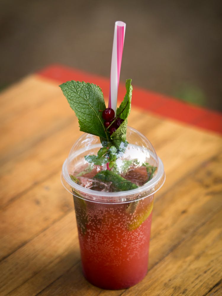 Clear Plastic Cup With Cranberry Flavored Drink On A Wooden Table