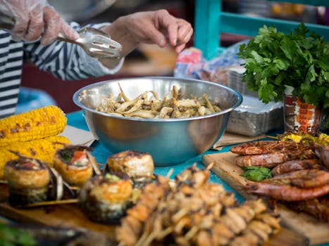 Vibrant street food scene featuring grilled seafood, skewers, and corn with fresh herbs.