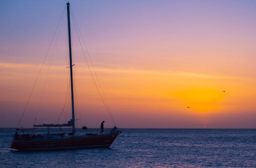 A Person Riding on the Boat while Sailing on the Sea During Golden Hour