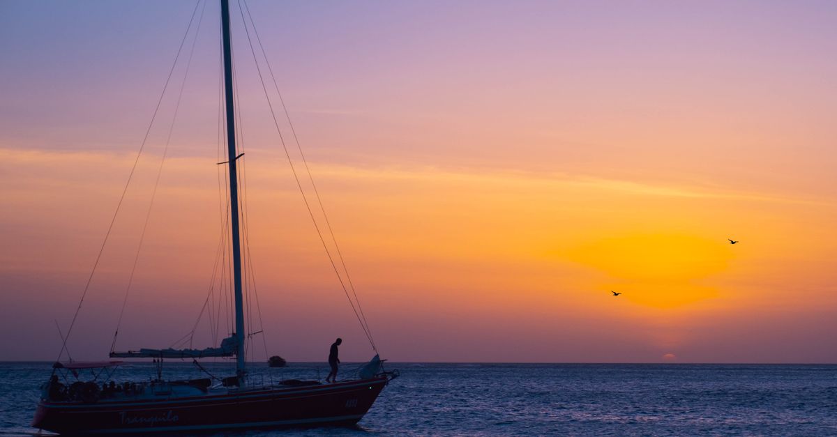 A Person Riding on the Boat while Sailing on the Sea During Golden Hour ...