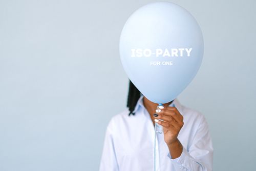Free Person with balloon reading 'ISO-PARTY FOR ONE' on a blue background, symbolizing isolation. Stock Photo
