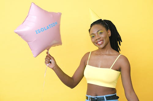 Woman in Yellow Spaghetti Strap Crop Top Holding a Pink Star Shaped Balloon