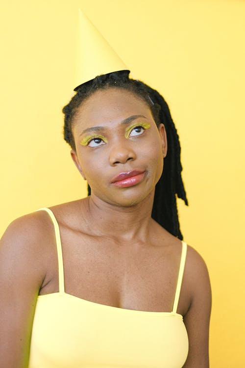 Gratis lagerfoto af afroamerikansk kvinde, fest hat, gul baggrund