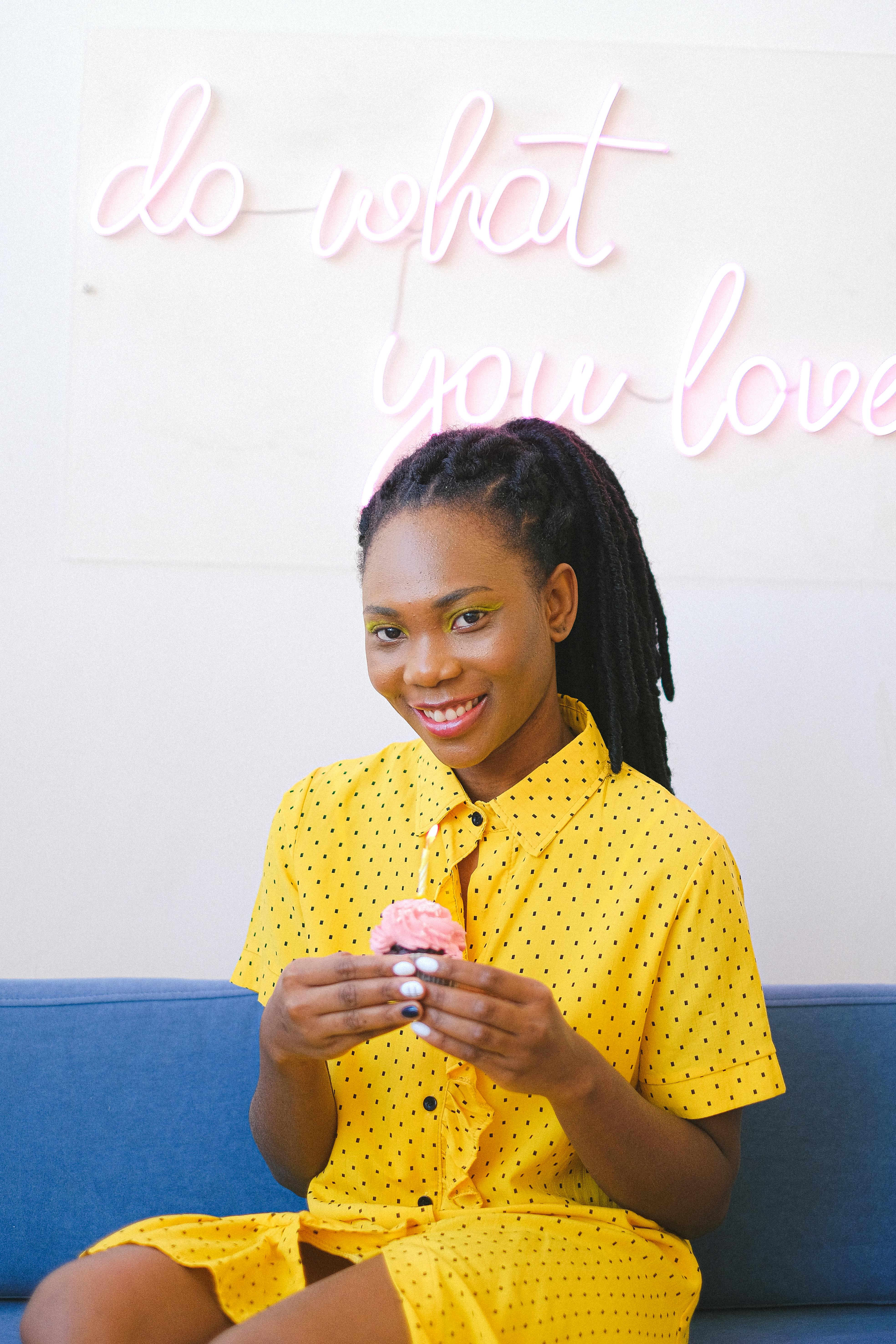 girl in yellow dress holding a cupcake while sitting on a couch