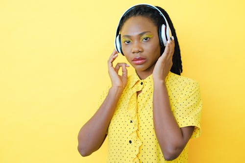 Woman in Yellow and Black Polka Dot Button Up Shirt Wearing Headphones
