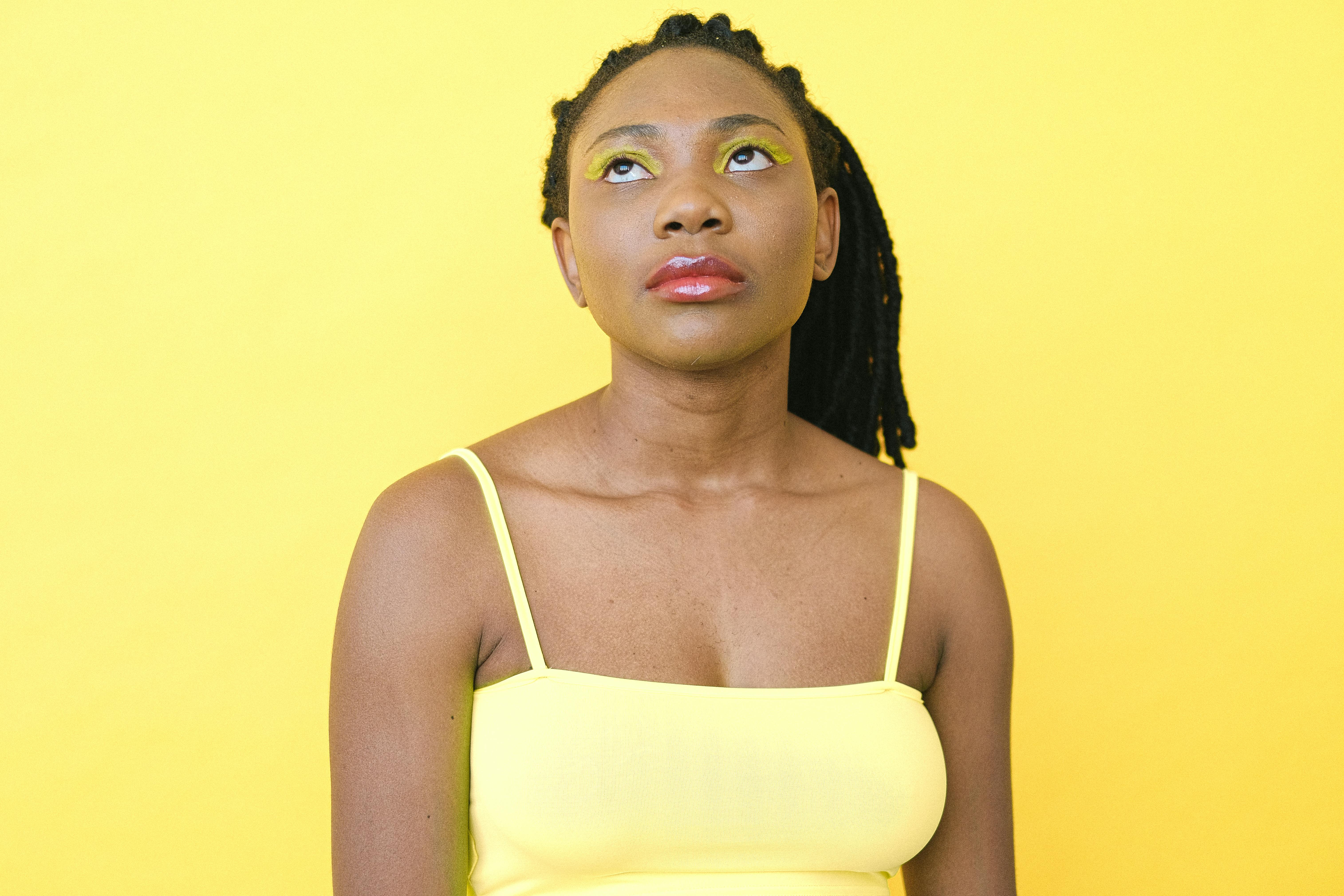 在充满活力的黄色背景下，一位女性抬头仰望的肖像引人注目