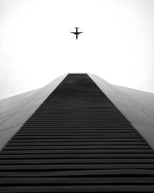 Airplane flying over modern skyscraper