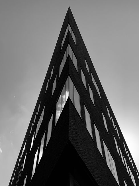 Black and white from below exterior of contemporary geometric office building against cloudless sky in city