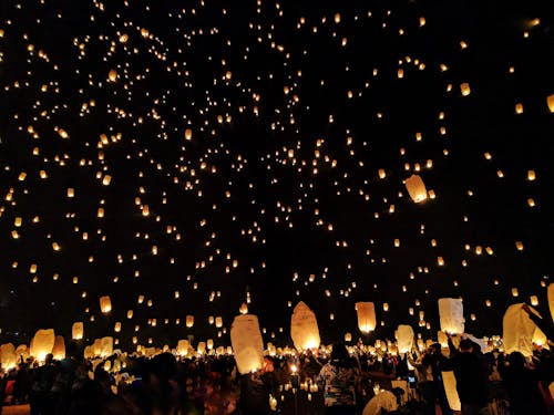 一群人在夜間將紙燈籠扔在天空上