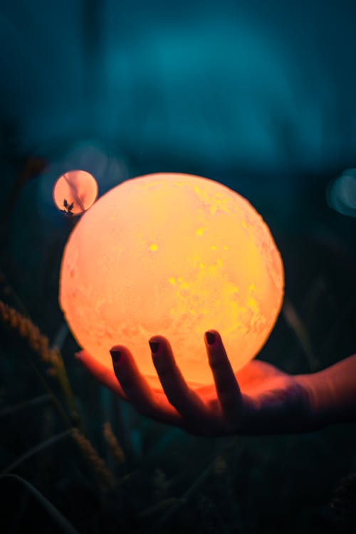 A Hand Holding a Moon Lamp
