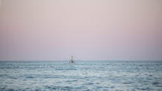 在宁静的暮光下，一艘孤独的渔船航行在平静的海面上，营造出一片宁静的海景