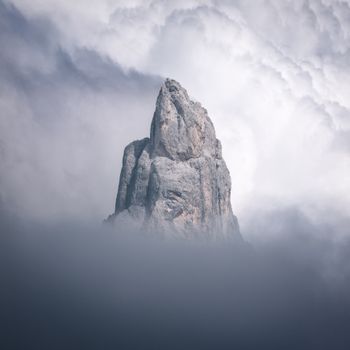 在意大利特伦蒂诺-上阿迪杰，一座令人惊叹的岩石山峰在浓雾中浮现，周围环绕着壮观的云层