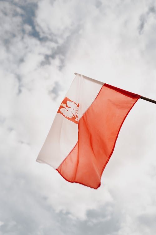 Free Bright flag of Poland under cloudy sky in city Stock Photo