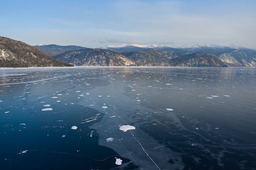 Amazing view of mountain ridge located on coast of frozen lake against blue sky in winter day