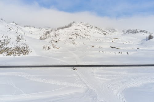 Modern car riding along road against snowy hills
