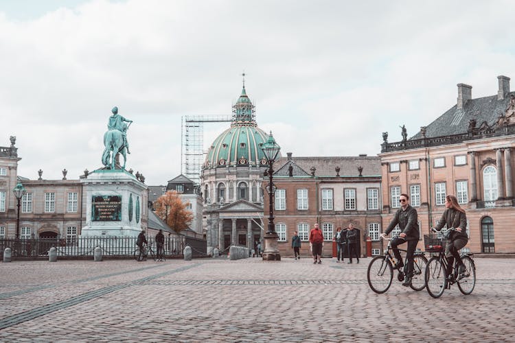 Old Church Facade Near Square With People Riding Bicycles