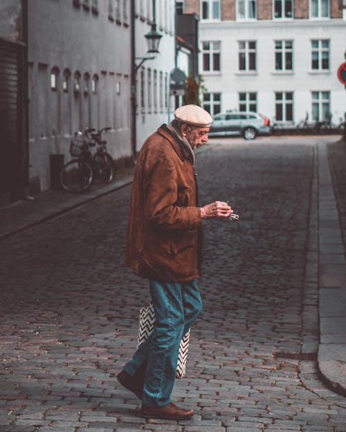 Elderly man walking on cobblestone walkway on city street
