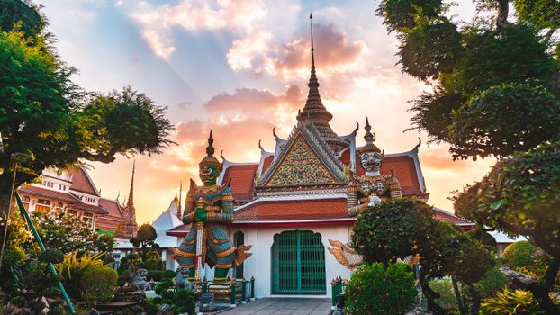 Stunning capture of Wat Arun in Bangkok with vibrant sunset and lush greenery.