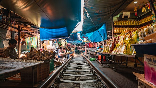 Explore the bustling Bangkok railway market filled with vendors and vibrant shops along the tracks.