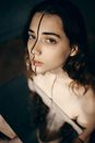 From above of young unhappy ethnic lady with black vertical line on face looking at camera while reflecting in mirror on black background