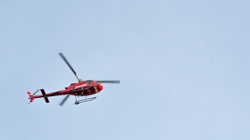 Bright red helicopter flying in blue sky