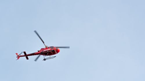 Free From below of colorful copter with metal blades and tail rotor flying in cloudless sky Stock Photo