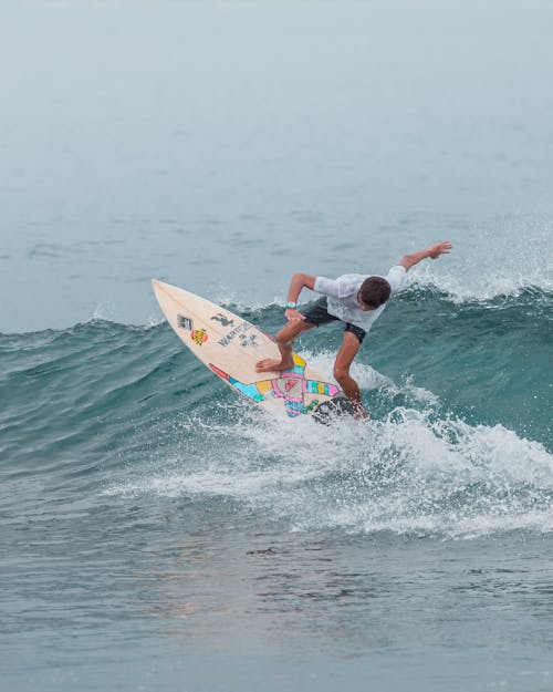 Man in White Shirt Surfing on Sea