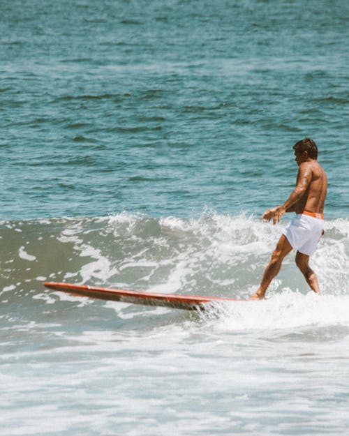 Man Wearing White Shorts Surfing on Sea