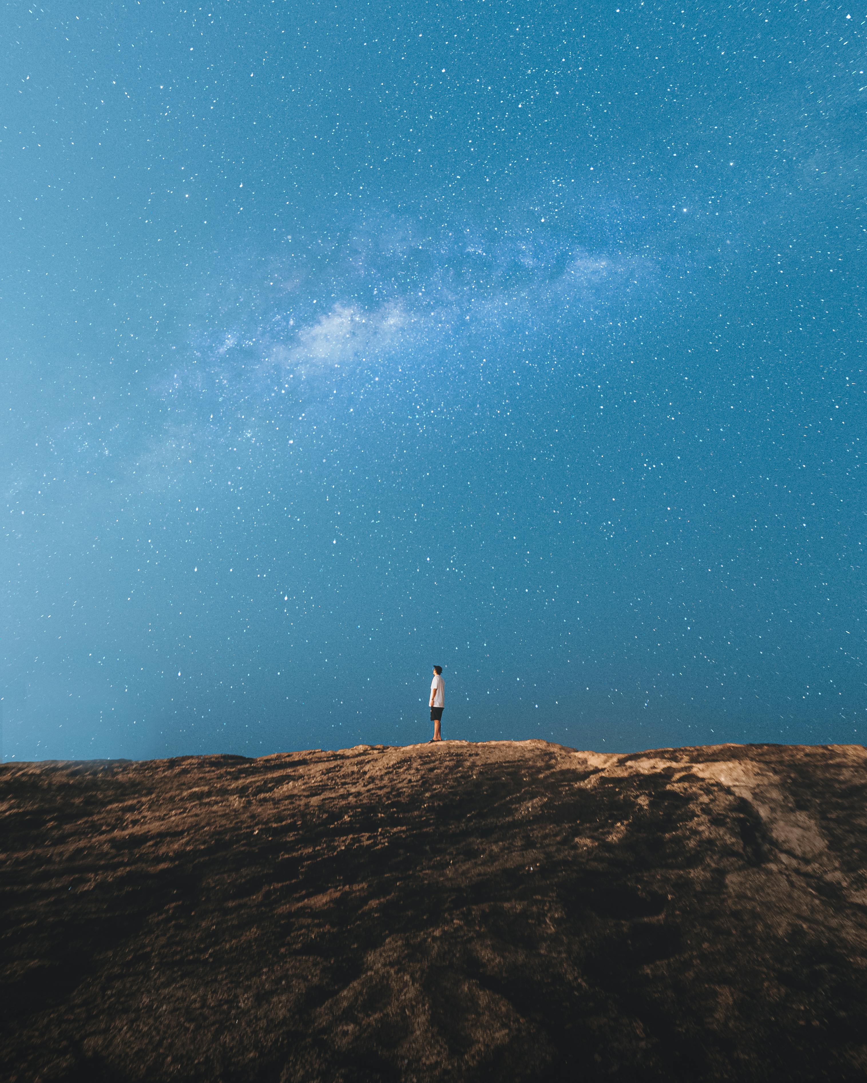 A traveler stands under the Milky Way on a rocky hill in Rio de Janeiro, Brazil.