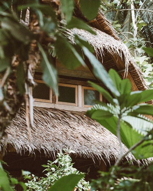 Free Explore the charm of a tropical wooden villa surrounded by lush greenery and natural textures. Perfect for vacation inspiration. Stock Photo