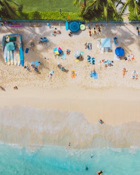 Aerial view of Waikiki Beach with umbrellas, surfboards, and sunbathers on a sunny day.