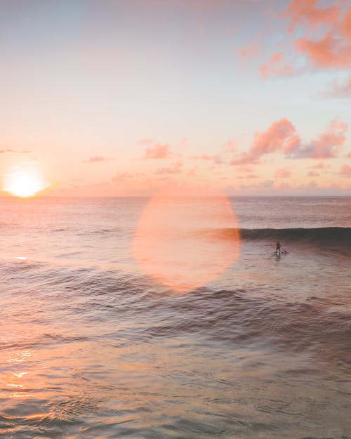Person Surfing on Sea during Sunset