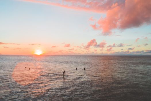 在夏威夷普普基亚海滩宁静的日落中，冲浪者正在桨板冲浪