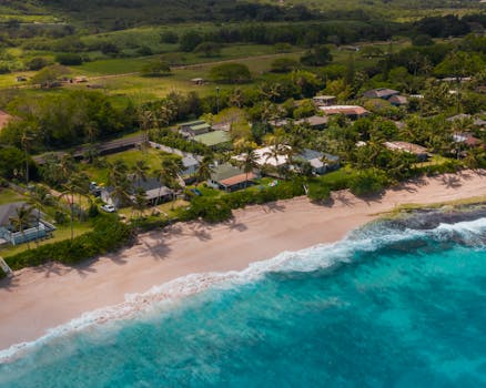A picturesque aerial view of beachfront homes along the sandy shores of Oahu, Hawaii.