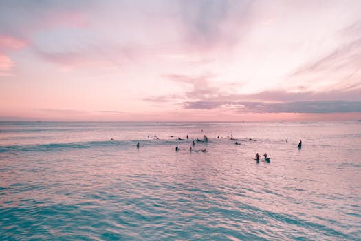Silhouettes of surfers at Waikiki Beach during a vibrant sunset in Honolulu, Hawaii.