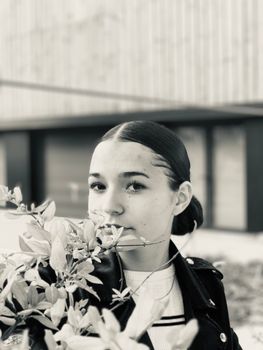 一位年轻女子手持树叶的黑白肖像，自然优雅地散发着魅力