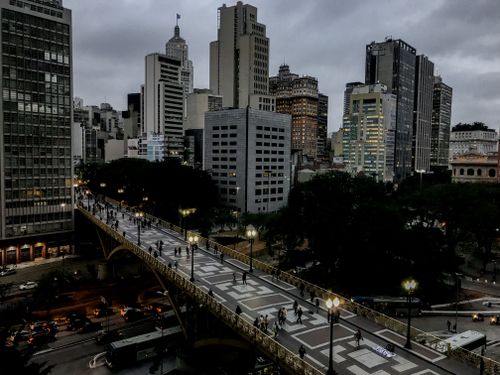 Free From above of modern bridge illuminated by street lamps near contemporary multistory building facades under cloudy sky in metropolis Stock Photo