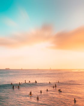 Capture the golden hour as surfers enjoy the serene sunset at Waikiki Beach, Hawaii.