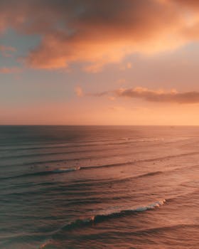 Warm sunset hues illuminate the ocean waves in Hawaii, creating a breathtaking seascape.