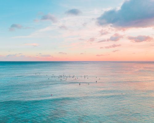Free A tranquil Oahu sunset over the Pacific Ocean with scattered surfers enjoying the view. Stock Photo