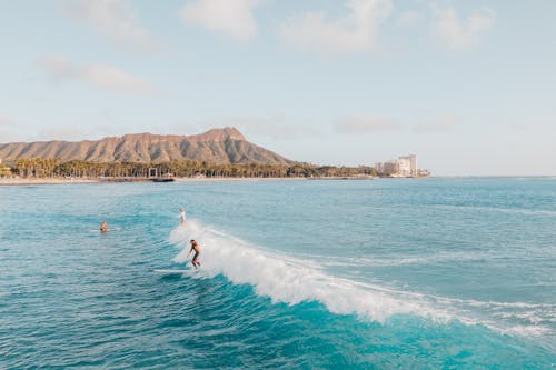 Person Surfing on Sea Near Mountain