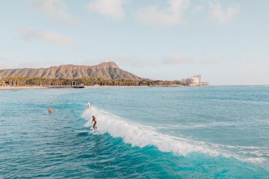 Surfers enjoy waves at Diamond Head, Hawaii, with scenic ocean and mountain views.