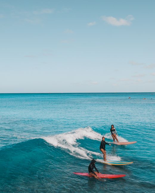 A group of surfers catching waves in the pristine waters of Oahu, Hawaii, showcasing perfect island harmony.