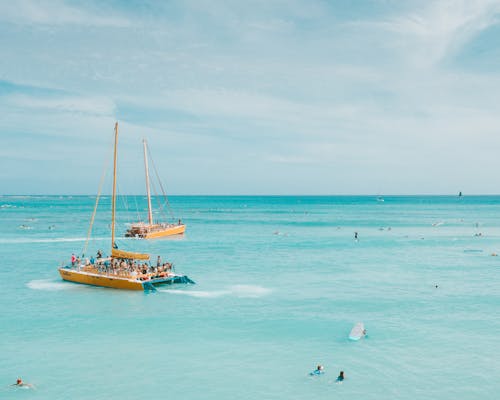 Free People on White and Yellow Boat on Sea Stock Photo