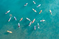 冲浪者在夏威夷海岸充满活力的蓝色海洋中划船的航拍照片