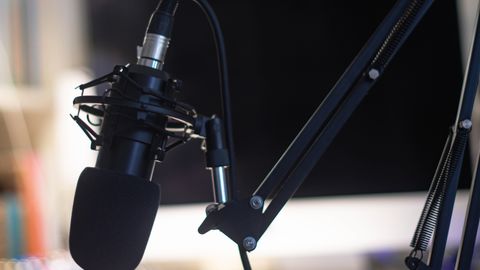 Close-up of a condenser microphone in a studio setting, ideal for podcasts and audio recording.